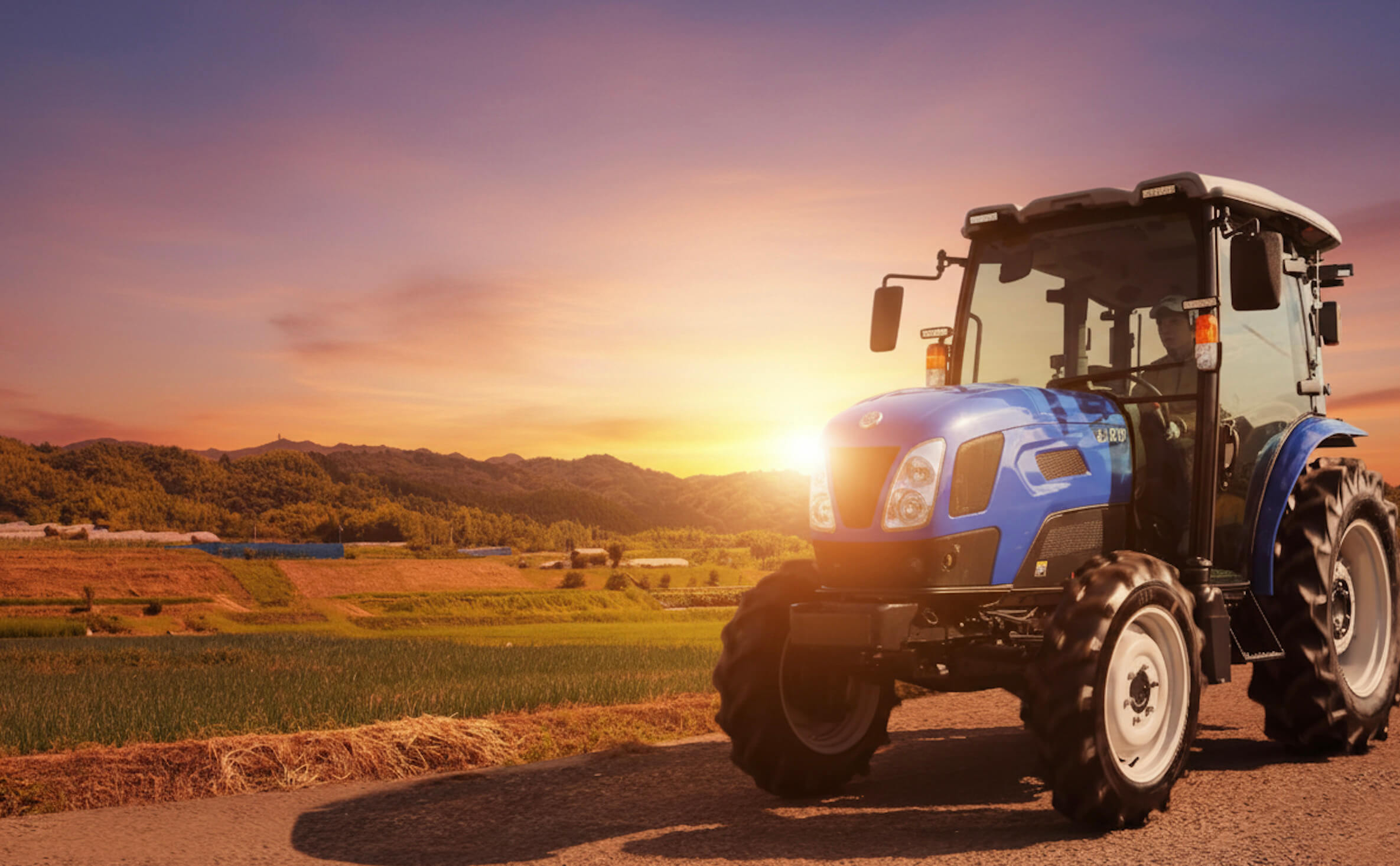 夕焼けの畑と青いトラクター