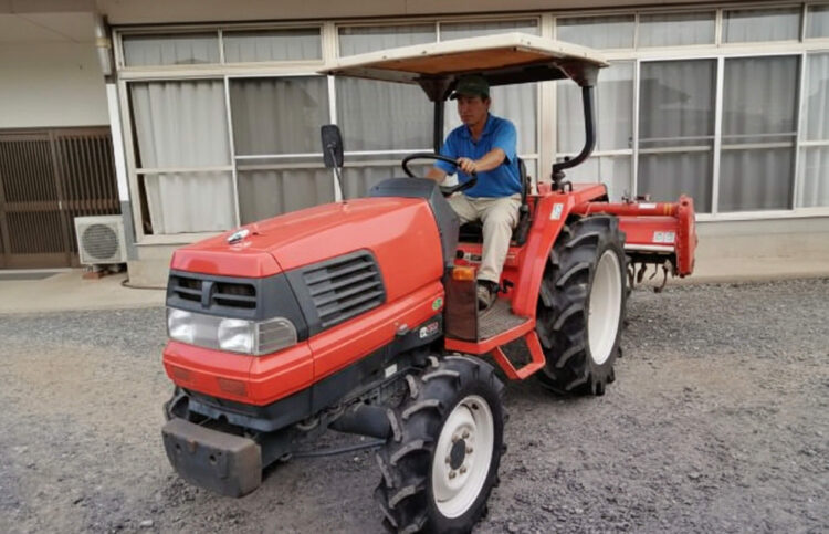 赤いトラクターに乗る男性