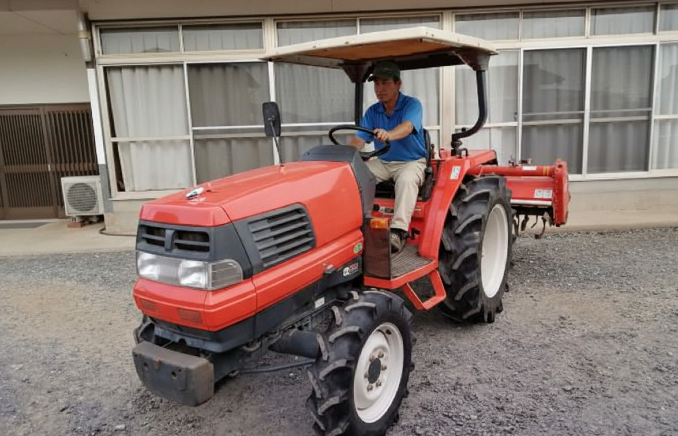 赤いトラクターに乗る男性