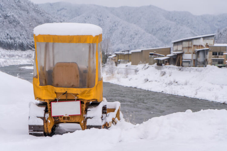 雪に覆われたトラクターと山村の風景