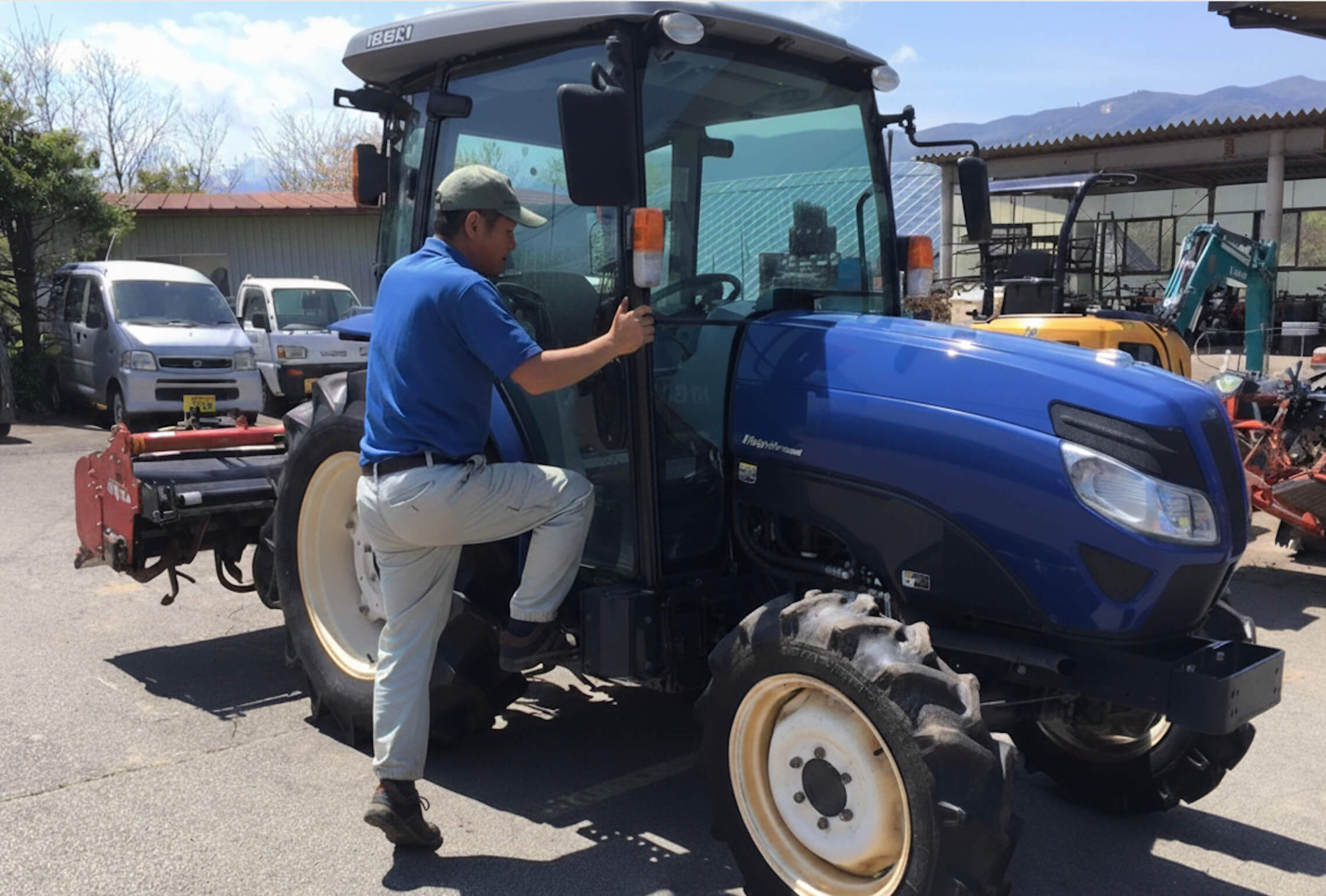 青いトラクターに乗り込む男性